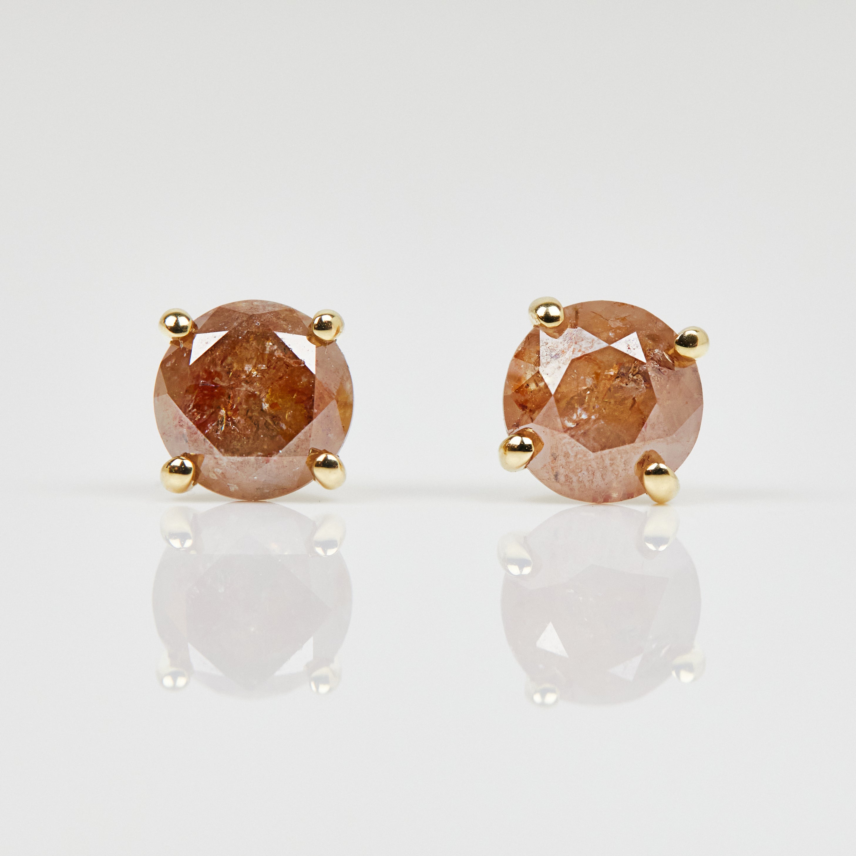 1ct round brilliant cut burnt orange diamonds set in 18ct yellow gold stud earrings.