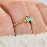 An 18ct yellow gold engagement ring with an oval green sapphire.
