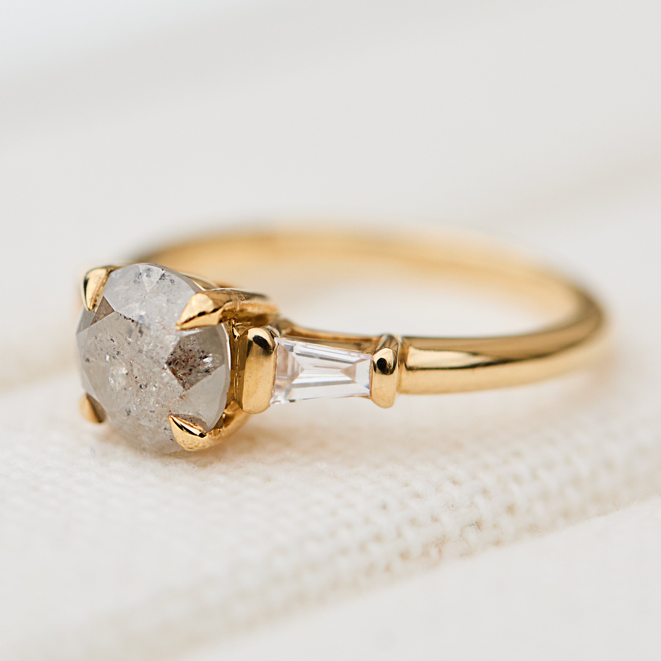 light grey round salt and pepper diamond trilogy engagement ring in yellow gold