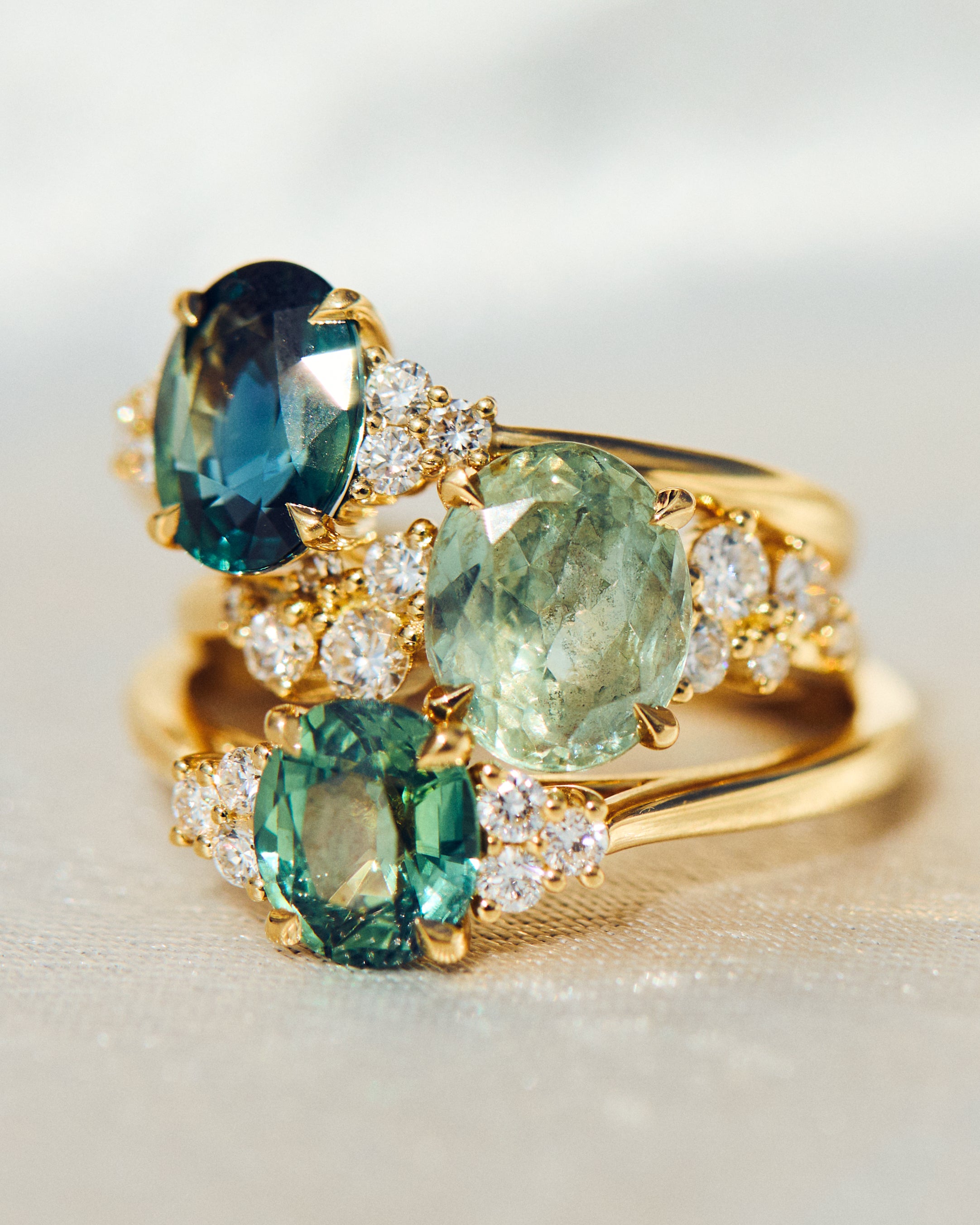 Gold ring with green gemstones on a light background