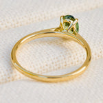 An 18ct yellow gold engagement ring with a green sapphire  in a prong setting.