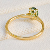 An 18ct yellow gold engagement ring with a green sapphire  in a prong setting.