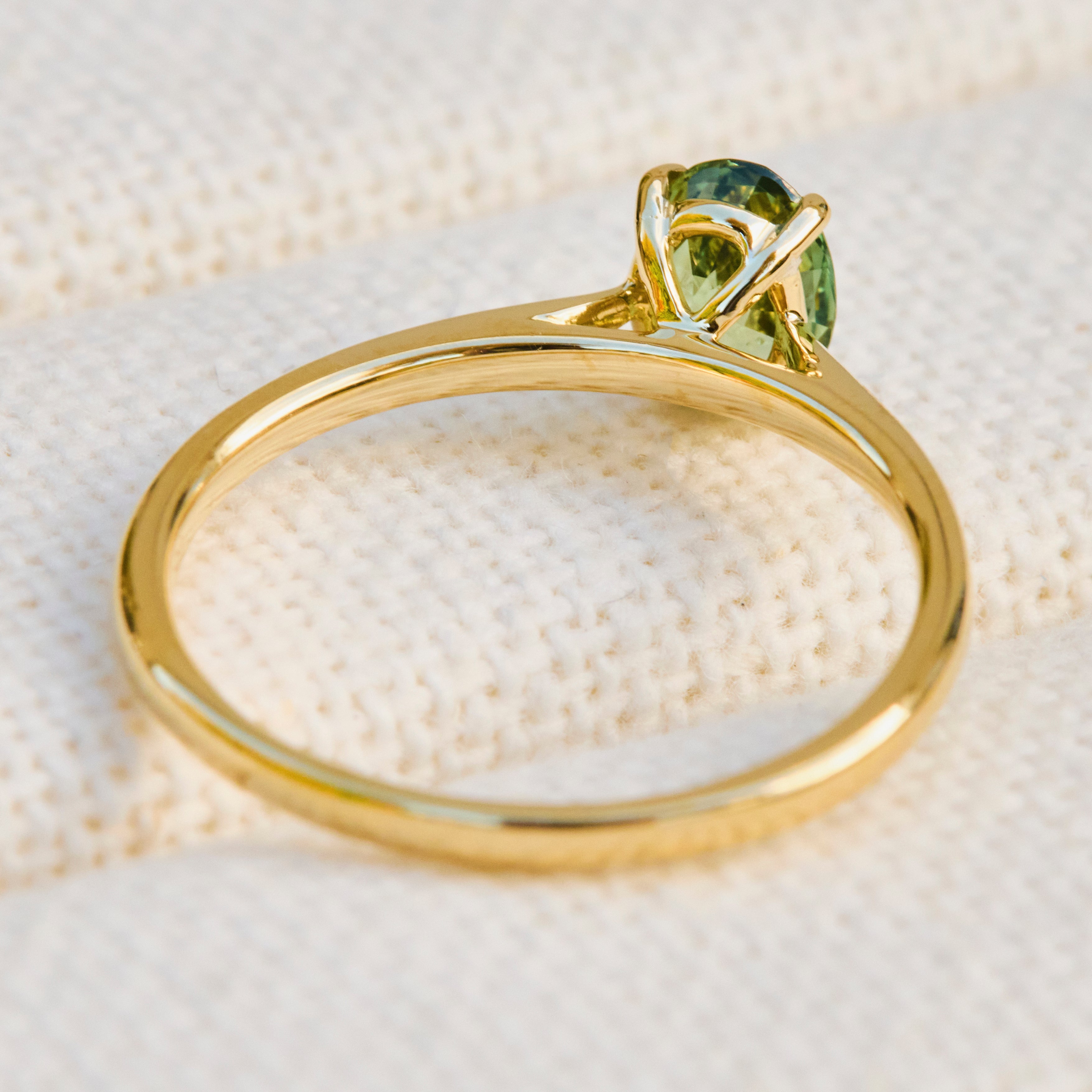 An 18ct yellow gold engagement ring with a green sapphire  in a prong setting.