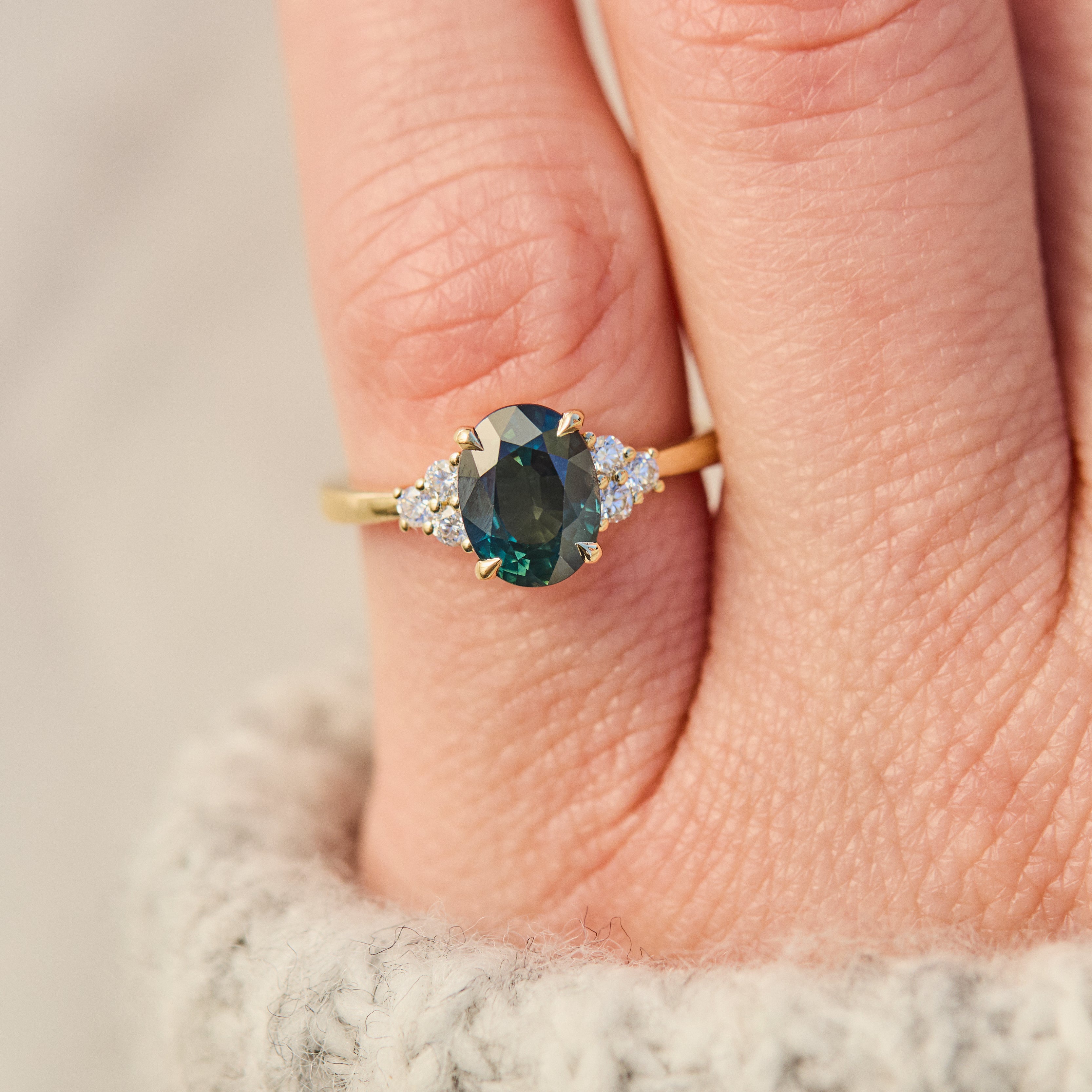 australian oval teal sapphire engagement ring with round diamond side stones