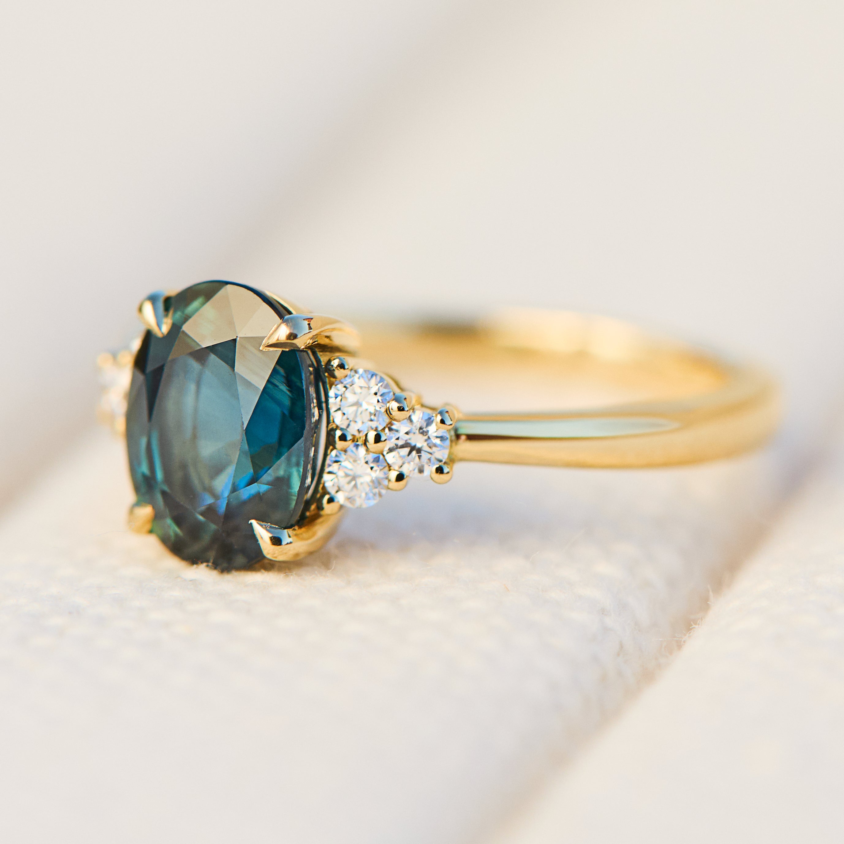 australian oval teal sapphire engagement ring with round diamond side stones