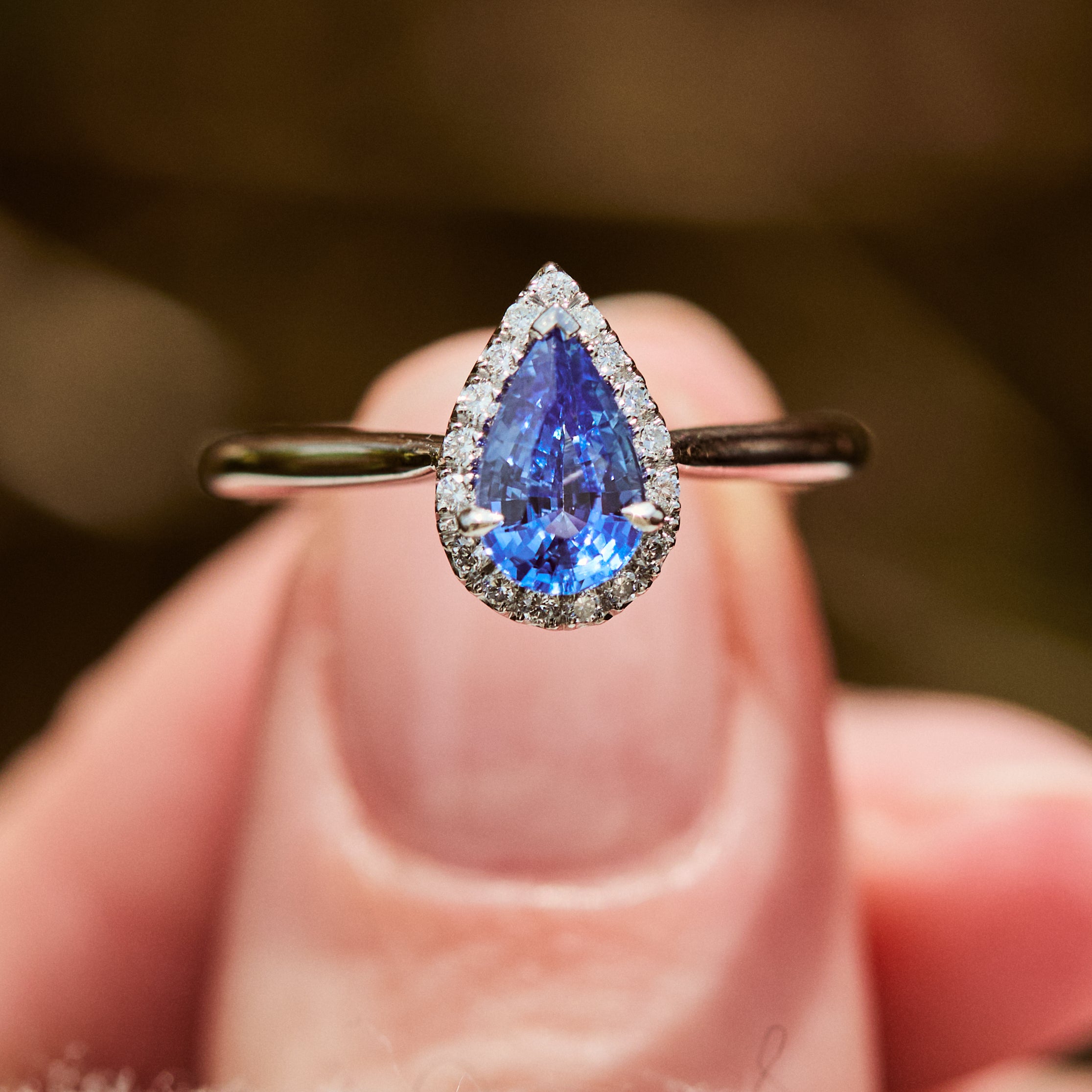 pear shape blue sapphire engagement ring with a pave diamond halo set in platinum