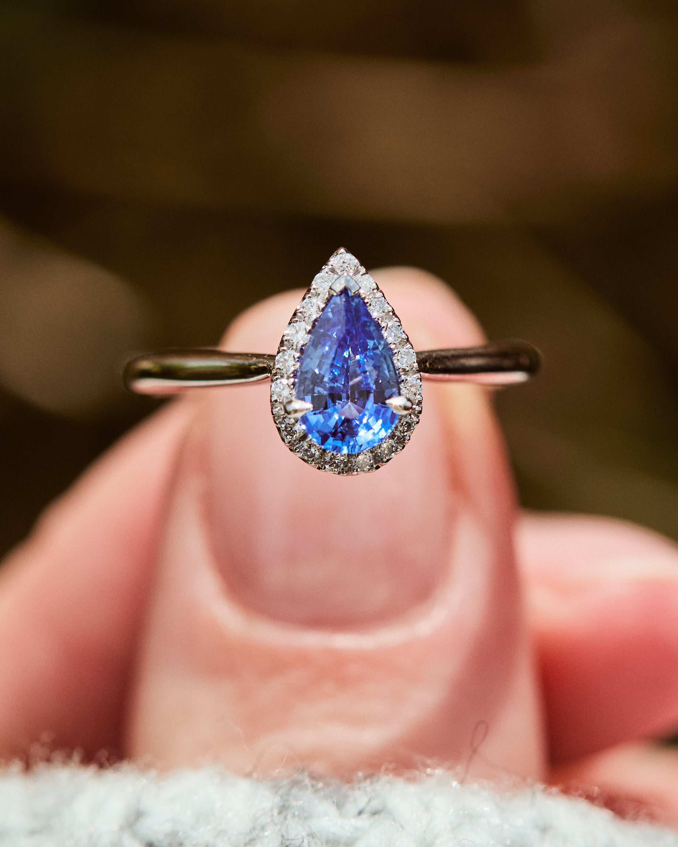 pear shape blue sapphire engagement ring with a pave diamond halo set in platinum