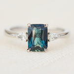 emerald cut blue teal sapphire trilogy engagement ring in platinum