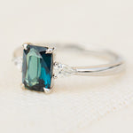 emerald cut blue teal sapphire trilogy engagement ring in platinum