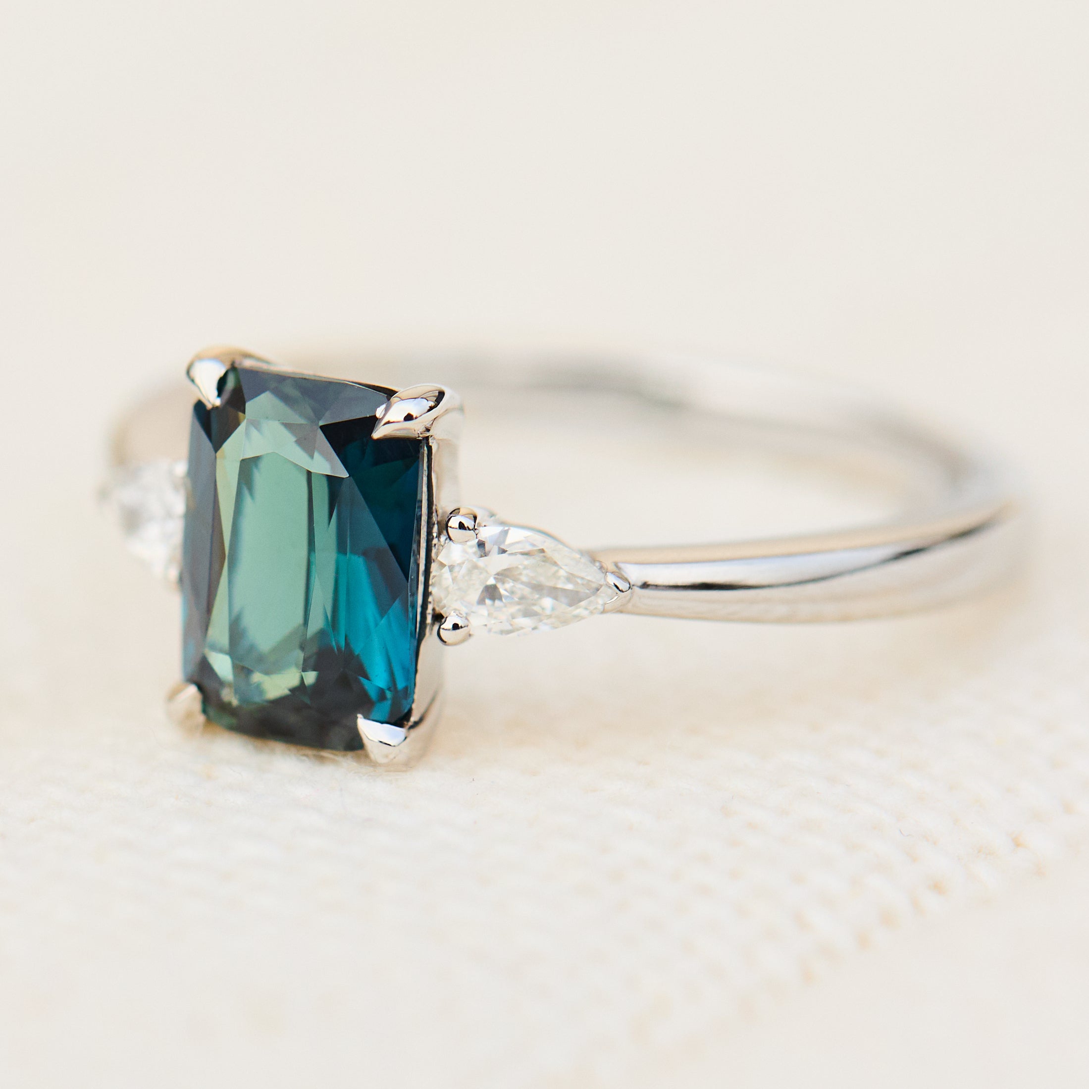 emerald cut blue teal sapphire trilogy engagement ring in platinum