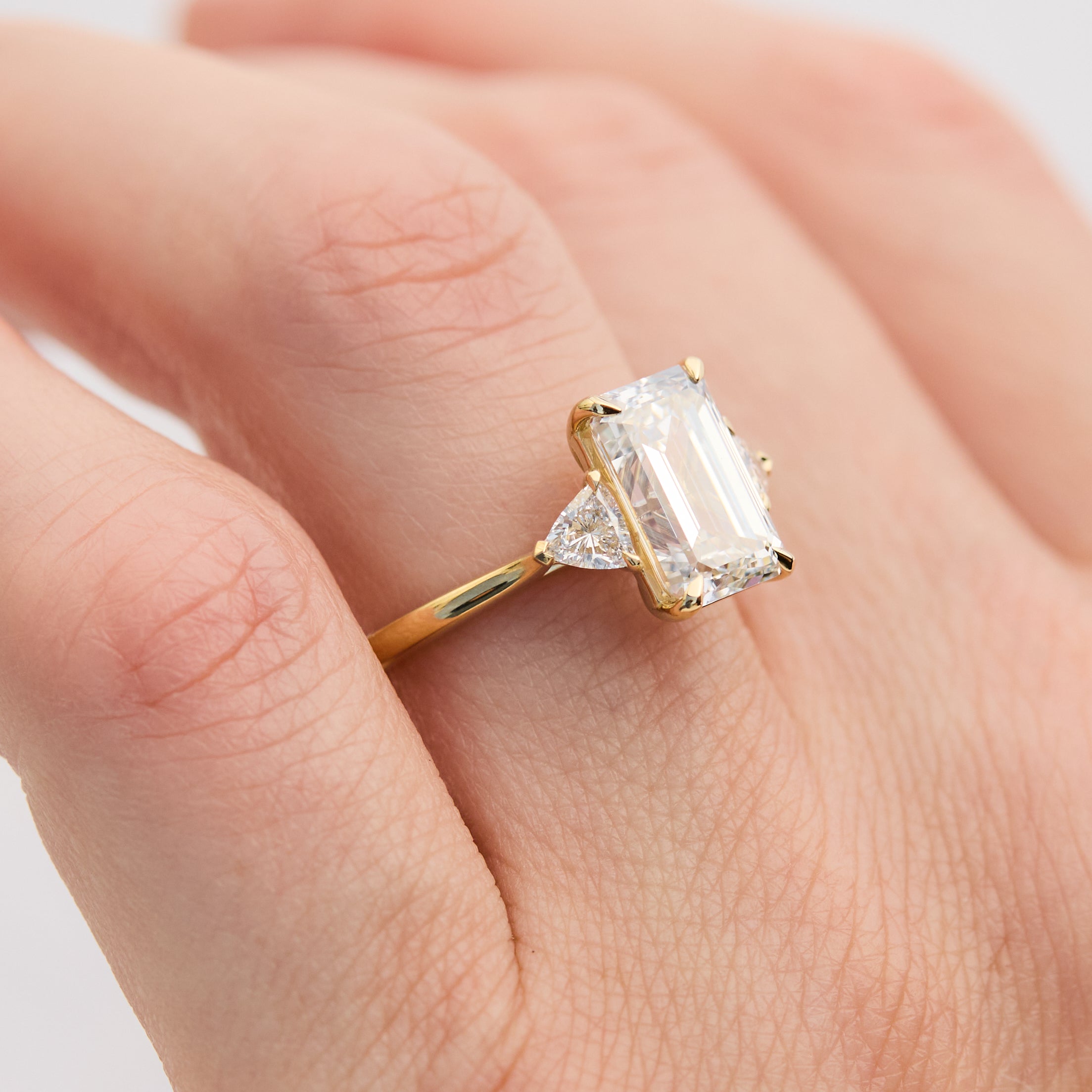 emerald cut lab grown diamond trilogy engagement ring set in yellow gold
