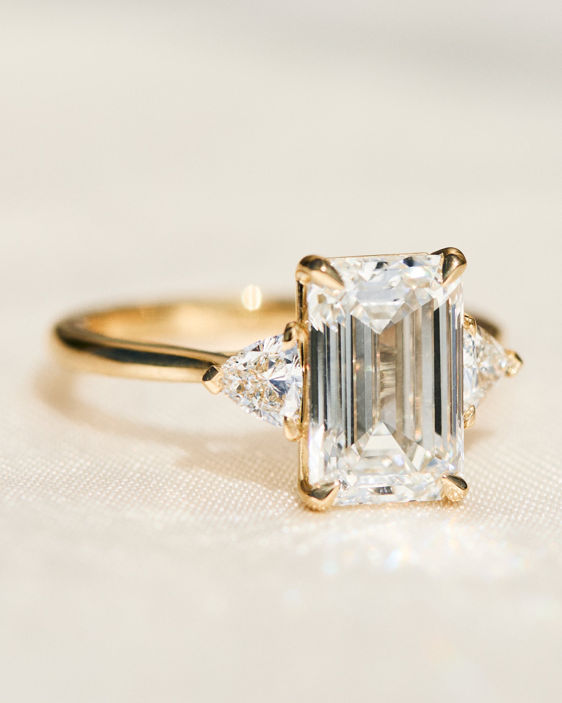 emerald cut lab grown diamond trilogy engagement ring set in yellow gold