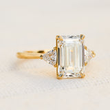 emerald cut lab grown diamond trilogy engagement ring set in yellow gold