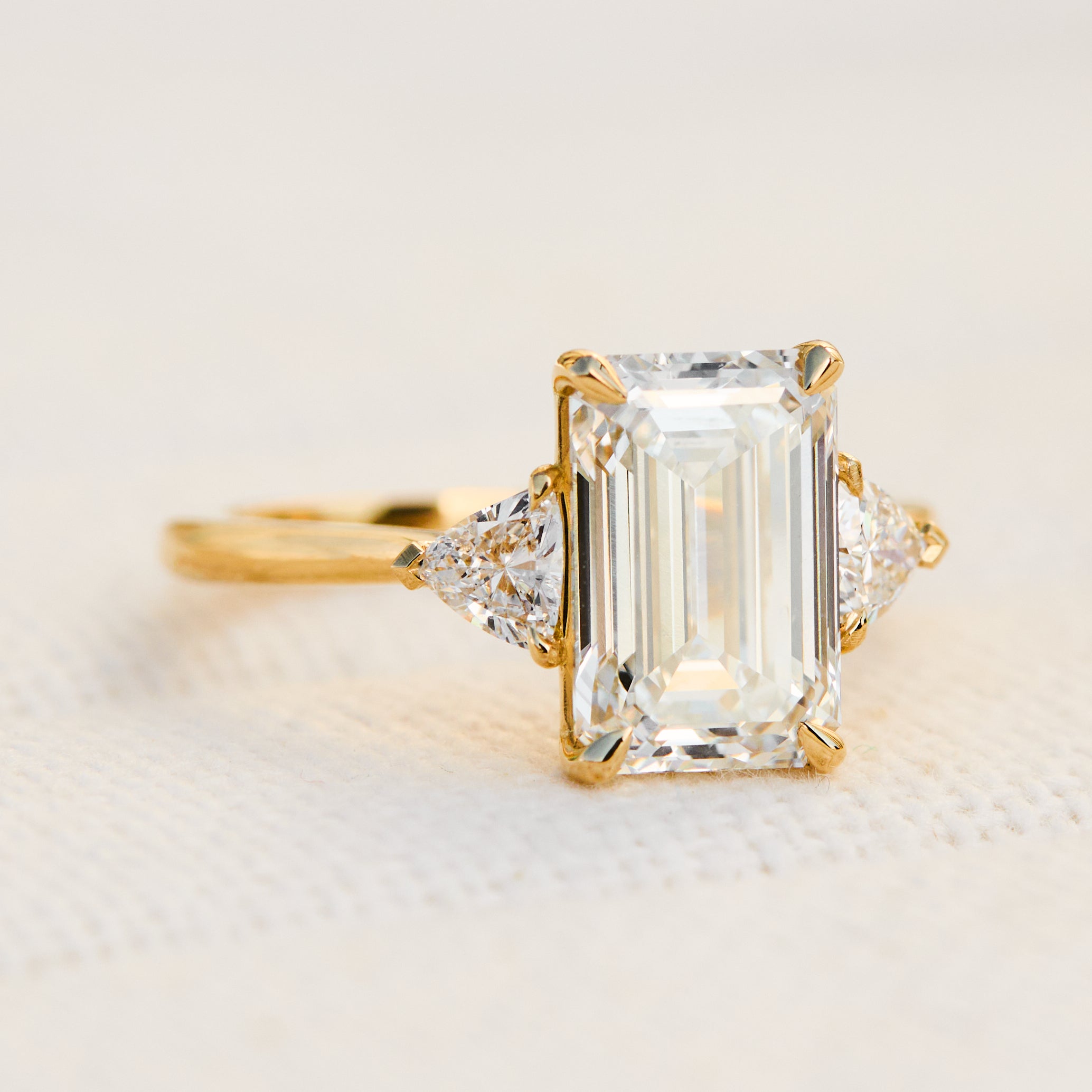 emerald cut lab grown diamond trilogy engagement ring set in yellow gold