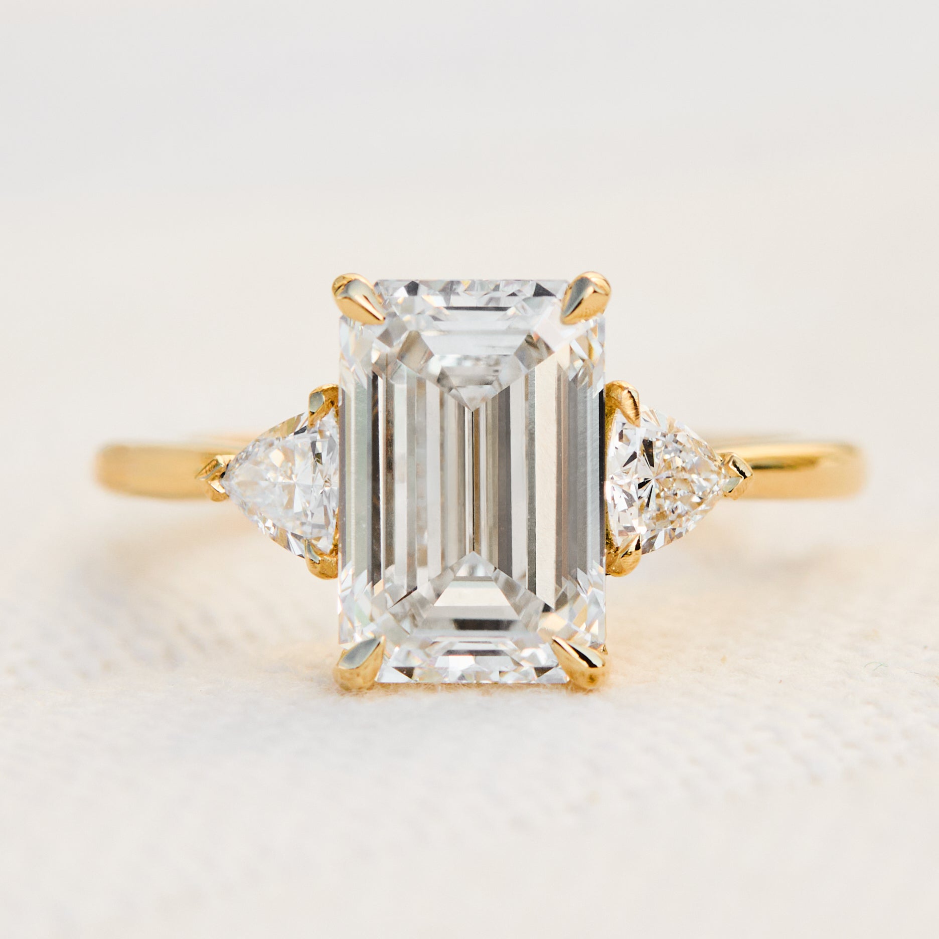 emerald cut lab grown diamond trilogy engagement ring set in yellow gold