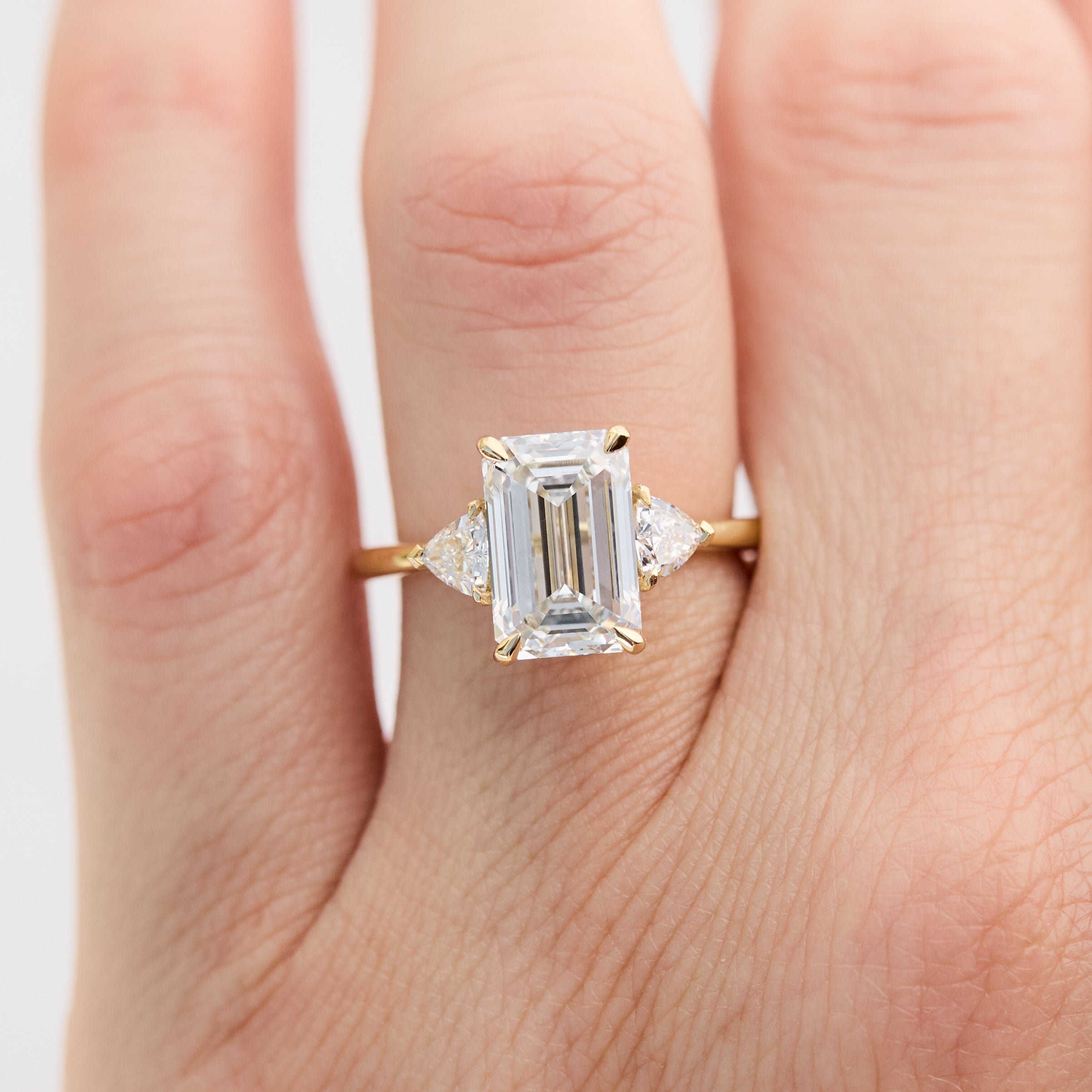emerald cut lab grown diamond trilogy engagement ring set in yellow gold