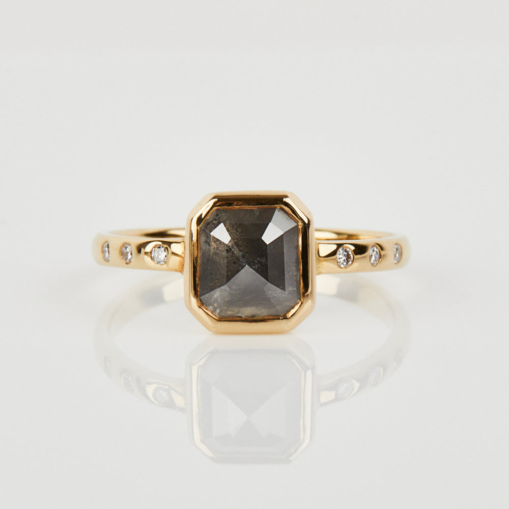 Emerald cut salt and pepper diamond engagement ring with six round white side diamonds set in 18ct recycled yellow gold