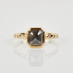 Emerald cut salt and pepper diamond engagement ring with six round white side diamonds set in 18ct recycled yellow gold