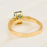 emerald cut teal sapphire trilogy engagement ring in yellow gold