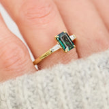 emerald cut teal sapphire trilogy engagement ring in yellow gold
