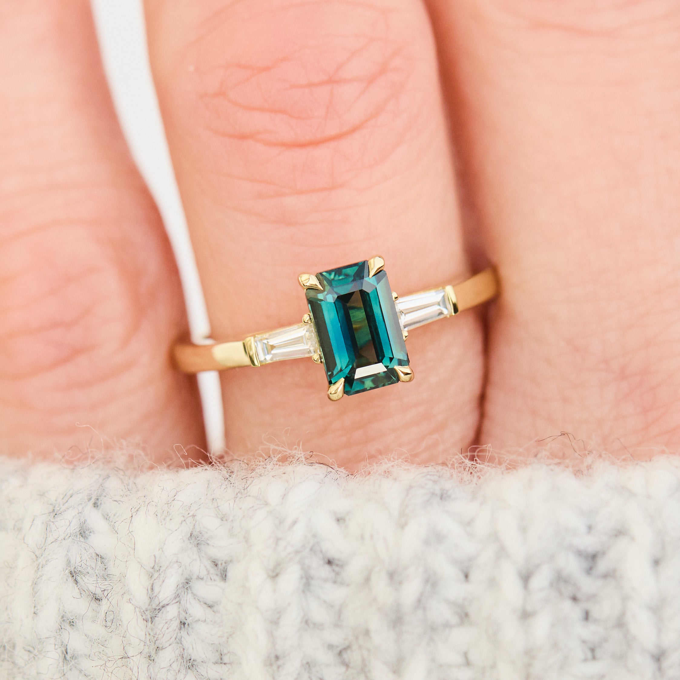 emerald cut teal sapphire trilogy engagement ring in yellow gold
