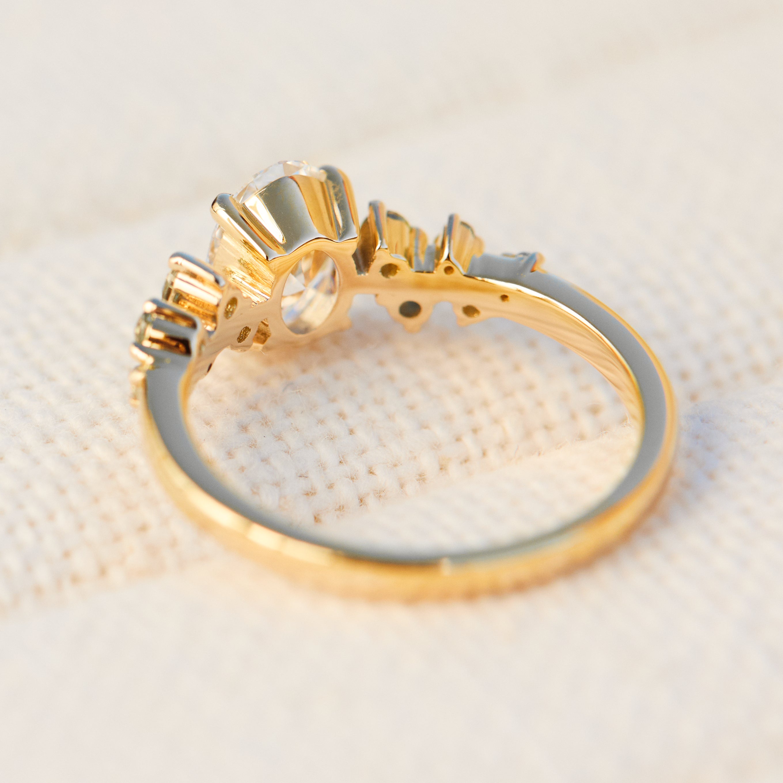 oval diamond engagement ring flanked by ten round side diamonds set in yellow gold