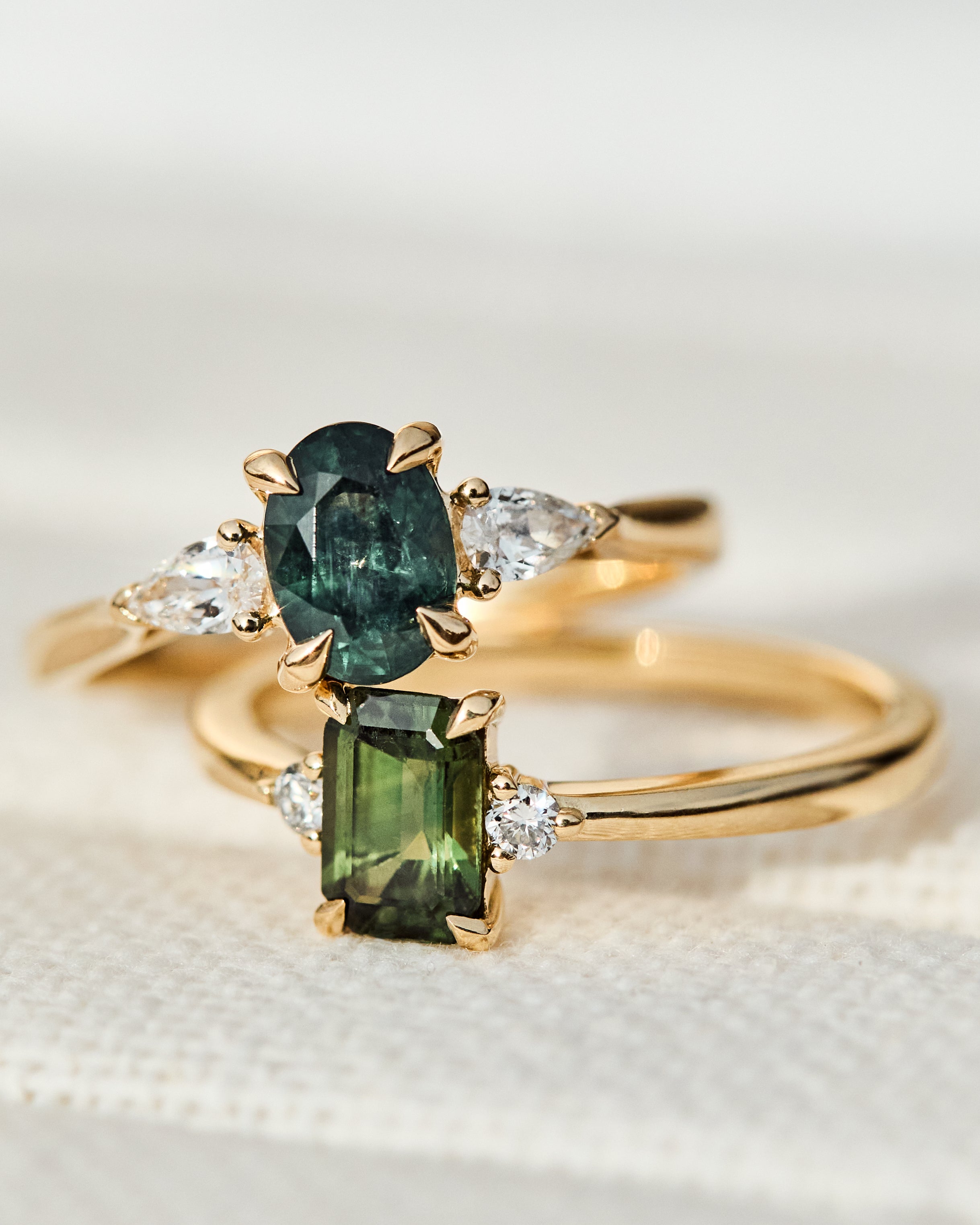 green oval and emerald cut sapphire rings in yellow gold