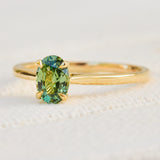 An 18ct yellow gold solitaire ring featuring an oval-cut green sapphire  in a prong setting.