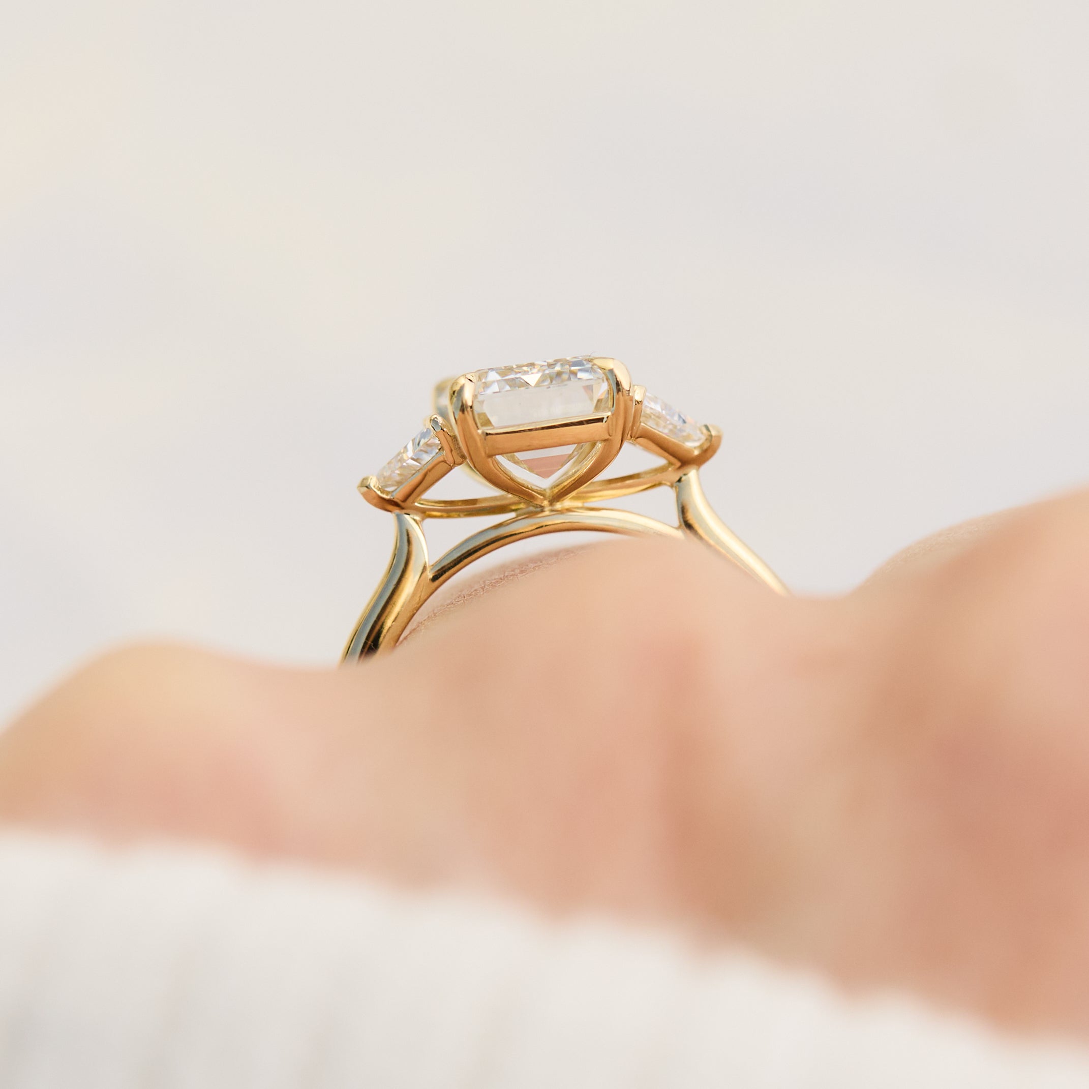 emerald cut lab grown diamond trilogy engagement ring set in yellow gold
