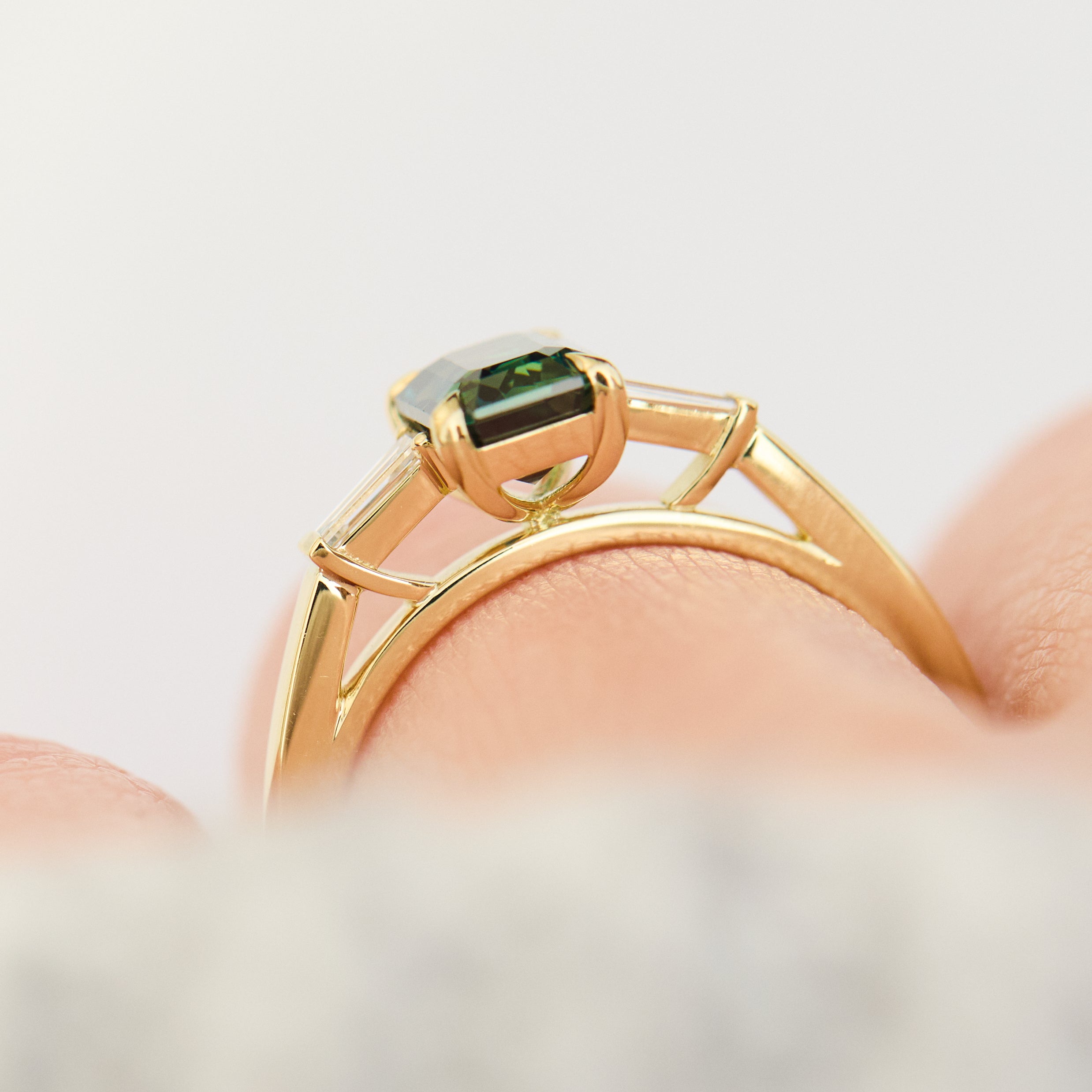 emerald cut teal sapphire trilogy engagement ring in yellow gold