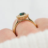 oval teal montana sapphire engagement ring in yellow gold with a diamond halo