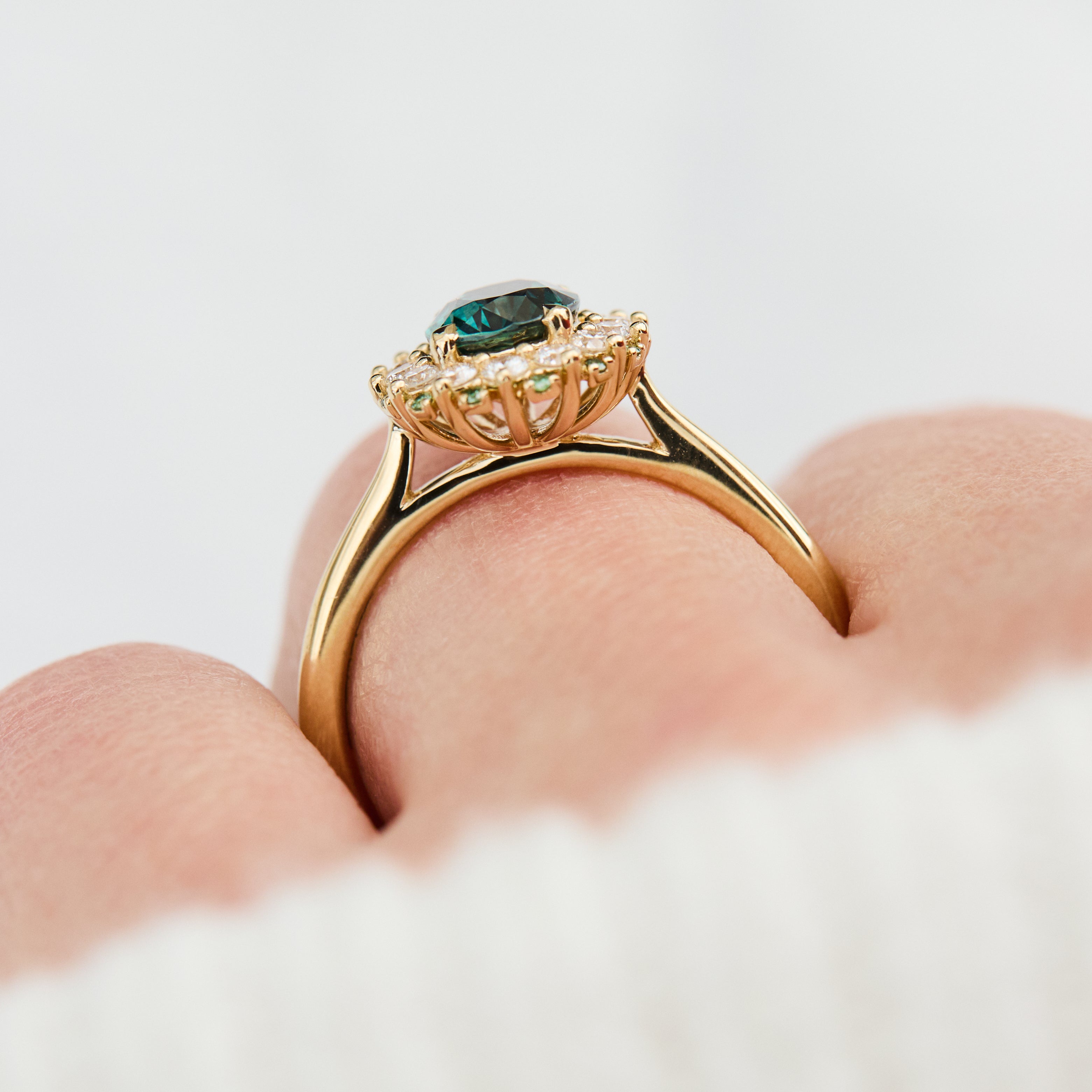 oval teal montana sapphire engagement ring in yellow gold with a diamond halo