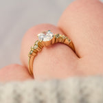 oval diamond engagement ring flanked by ten round side diamonds set in yellow gold