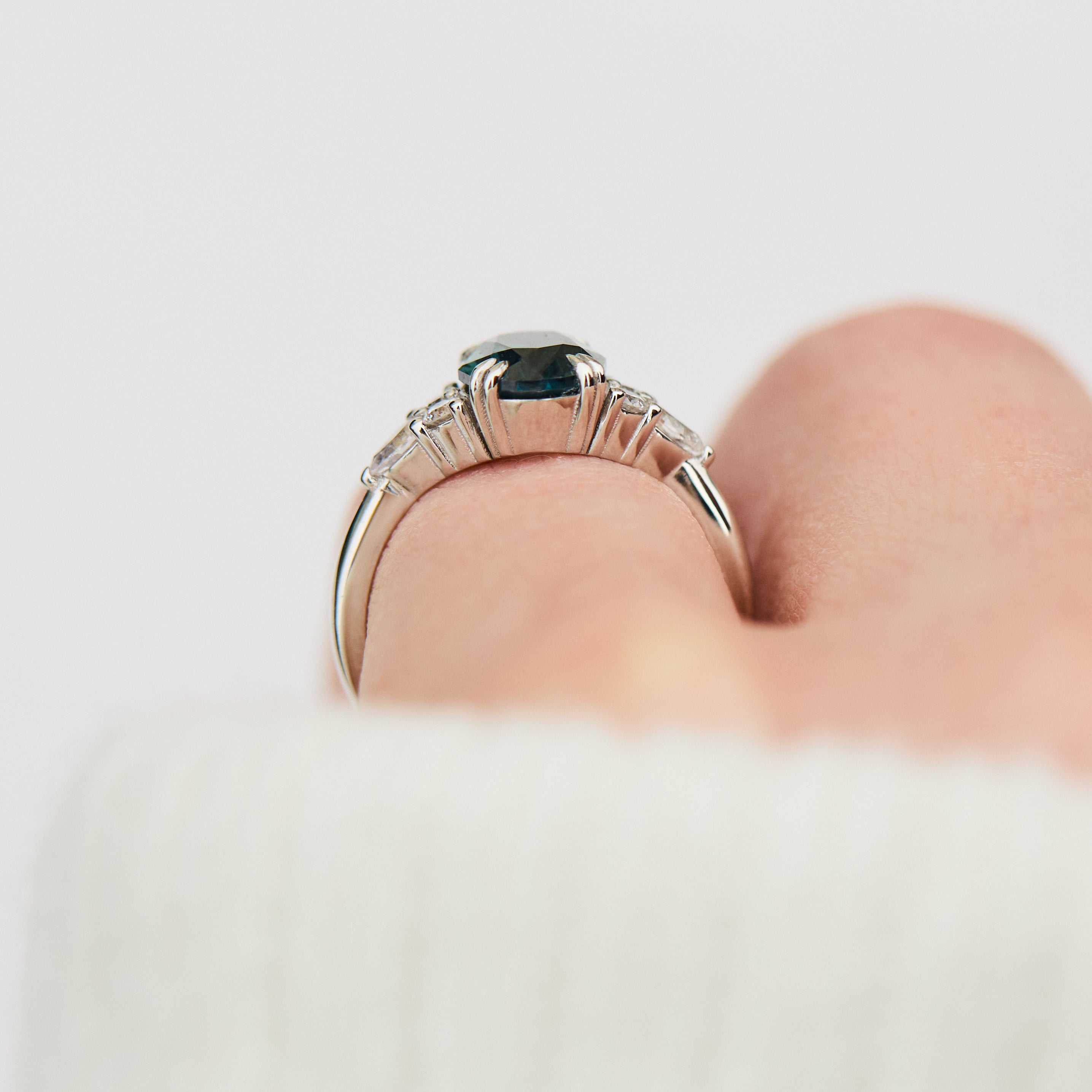 oval teal sapphire engagement ring set in platinum accented by six side diamonds