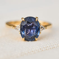 oval blue sapphire trilogy engagement ring in yellow gold