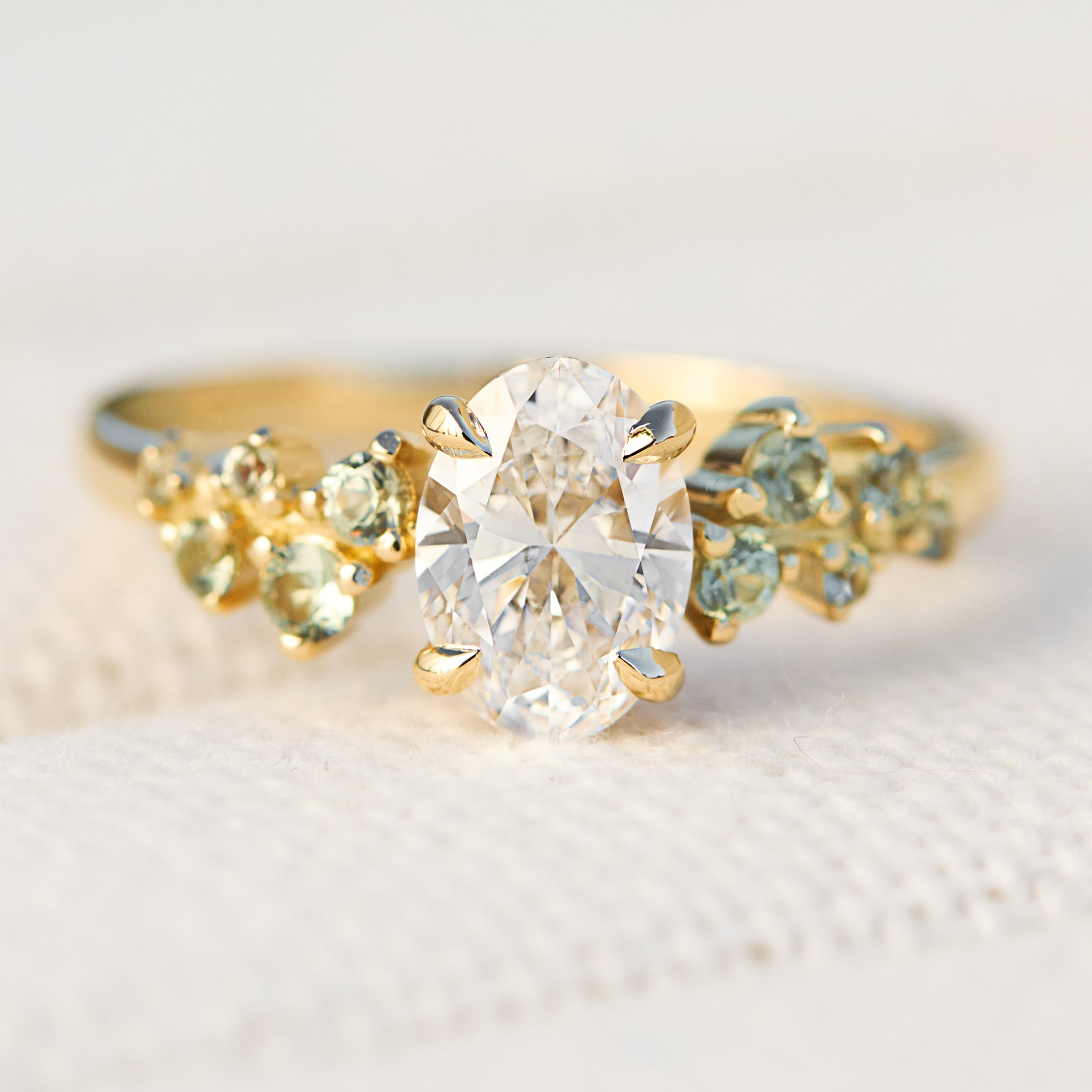 oval diamond engagement ring flanked by ten round side diamonds set in yellow gold