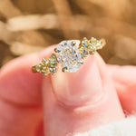 oval diamond engagement ring flanked by ten round side diamonds set in yellow gold