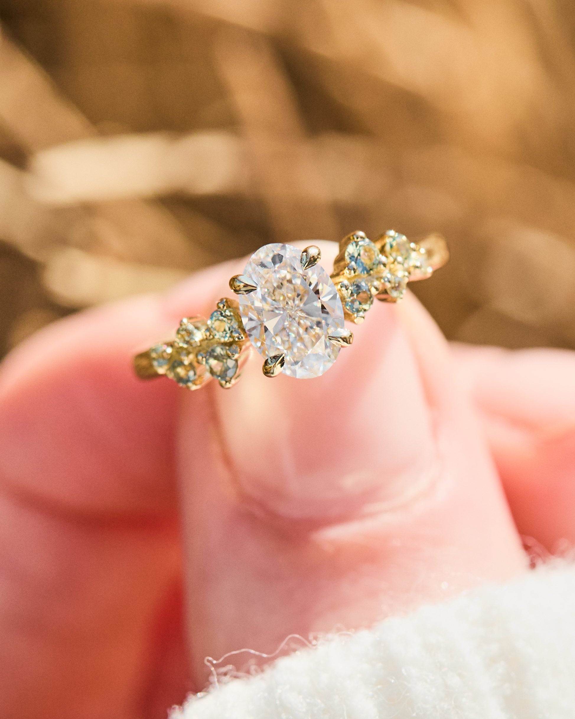 oval diamond engagement ring flanked by ten round side diamonds set in yellow gold