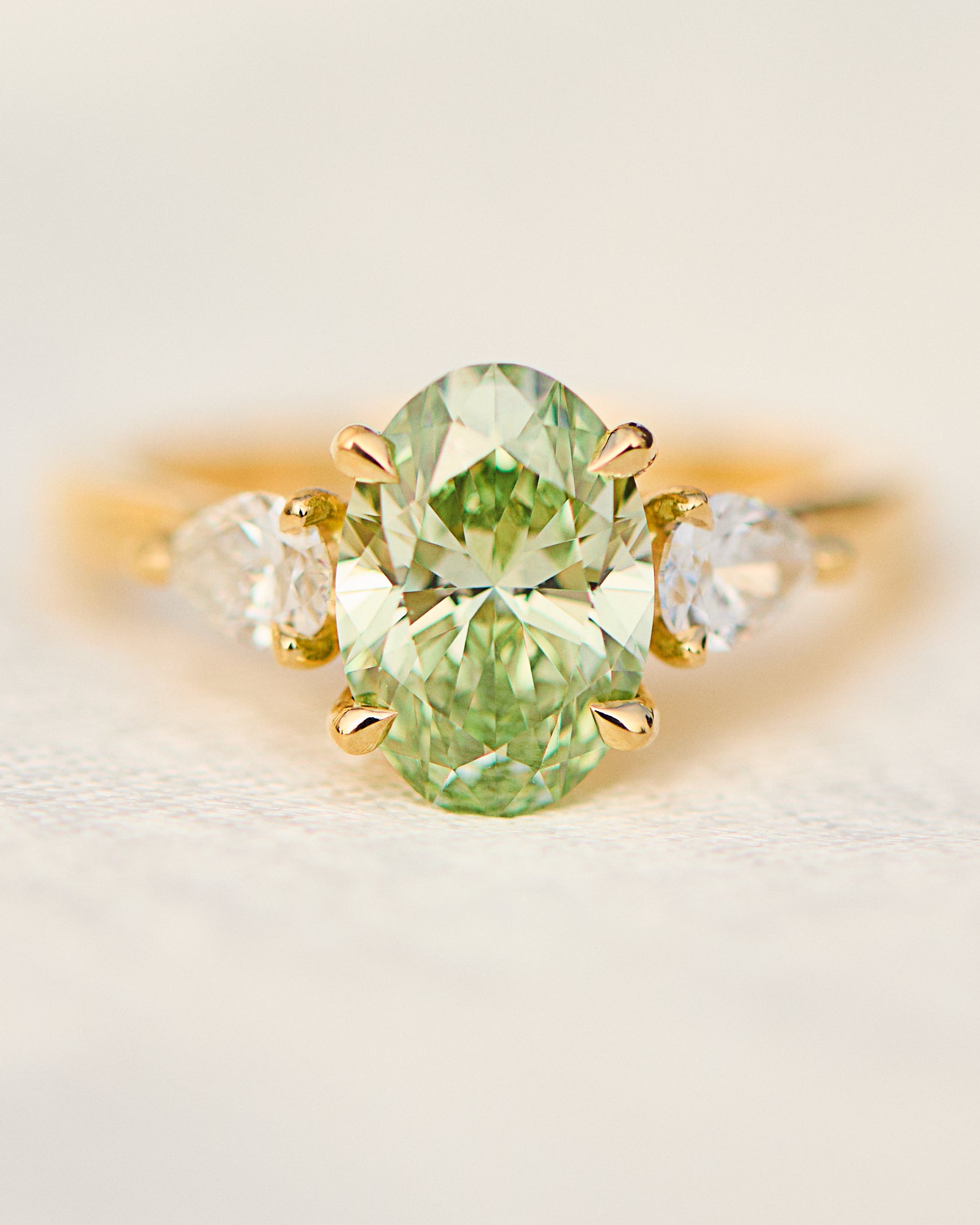 oval green lab grown diamond trilogy engagement ring in yellow gold