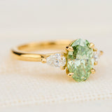 oval green lab grown diamond trilogy engagement ring in yellow gold