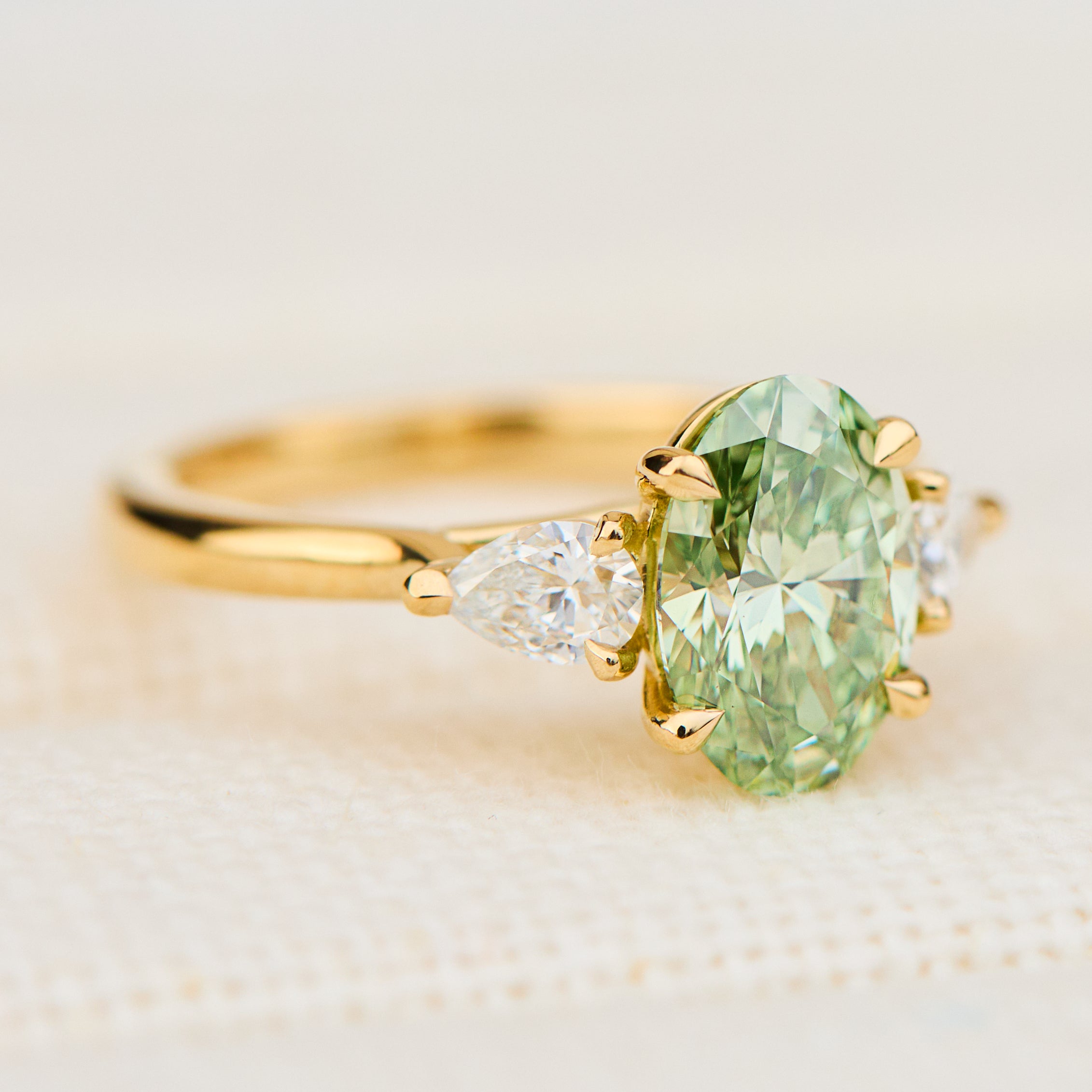 oval green lab grown diamond trilogy engagement ring in yellow gold