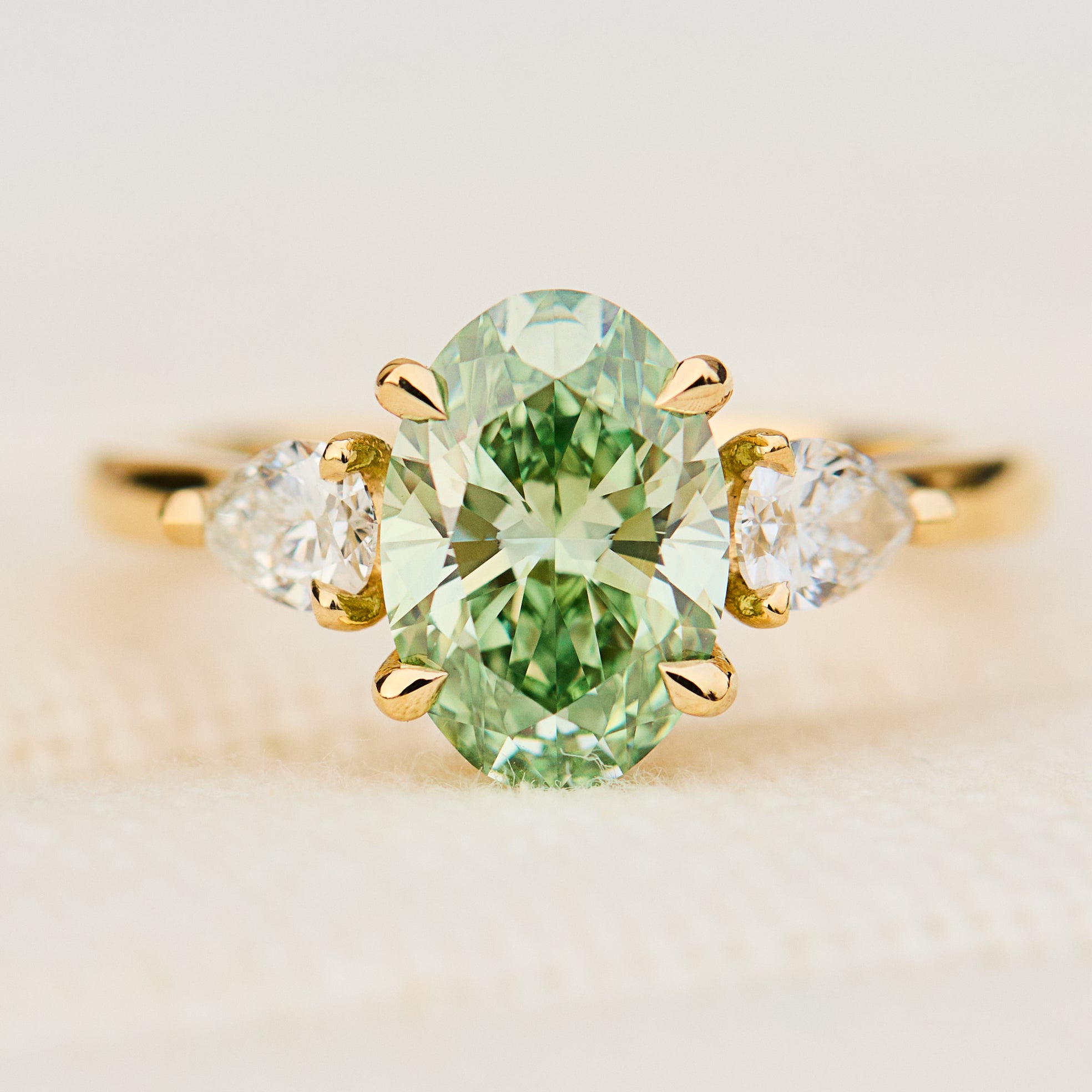 oval green lab grown diamond trilogy engagement ring in yellow gold