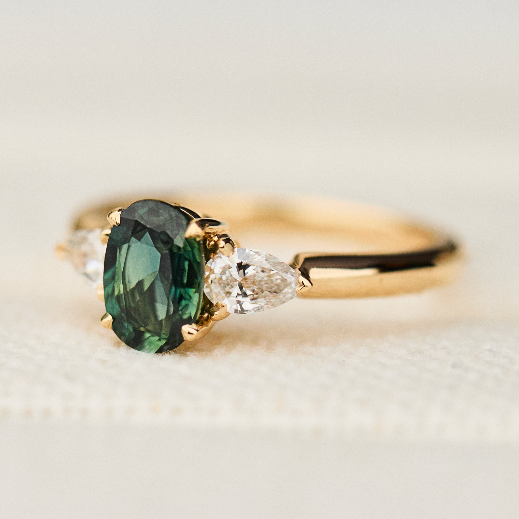 oval green sapphire trilogy engagement ring in yellow gold