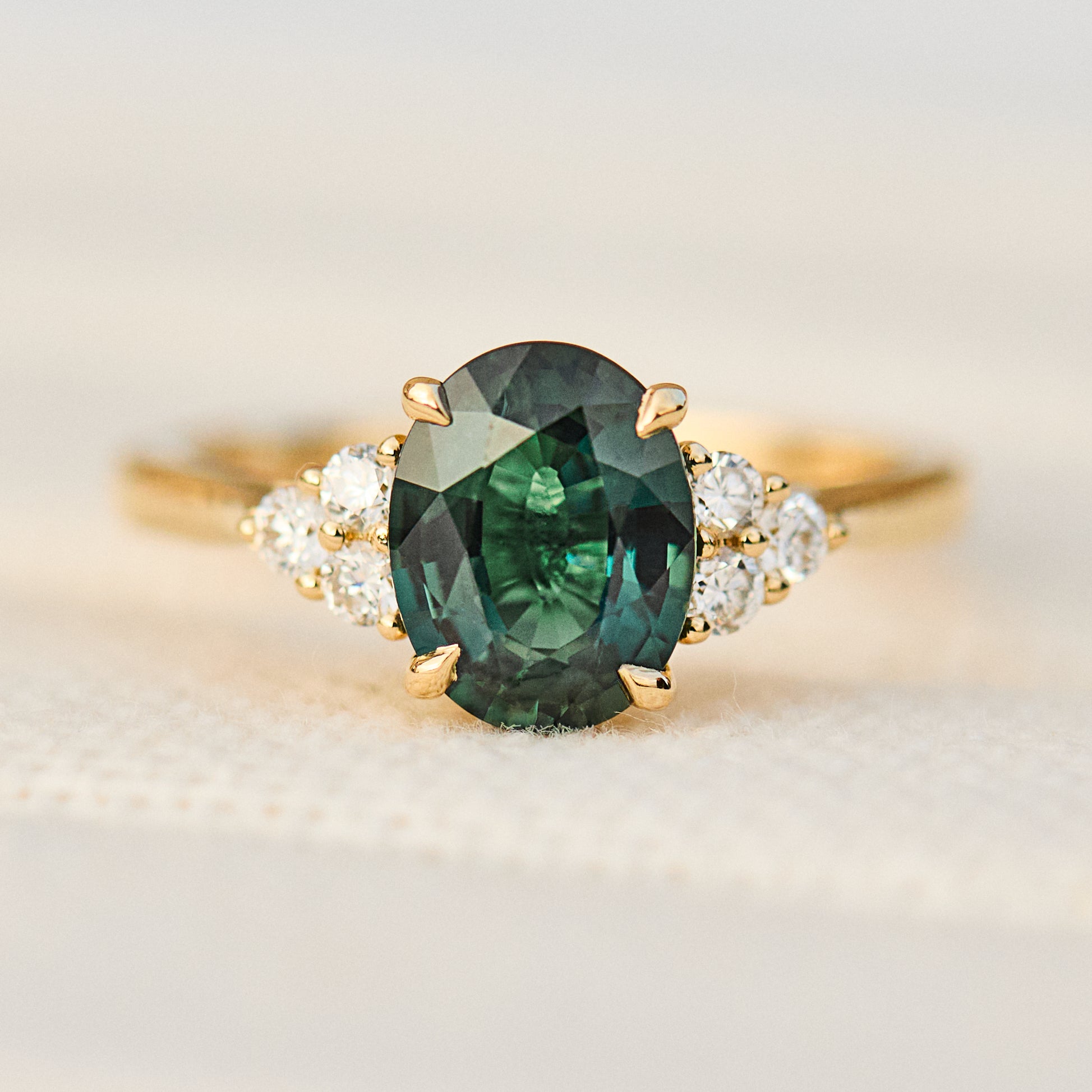 oval green teal sapphire engagement ring paired with diamonds