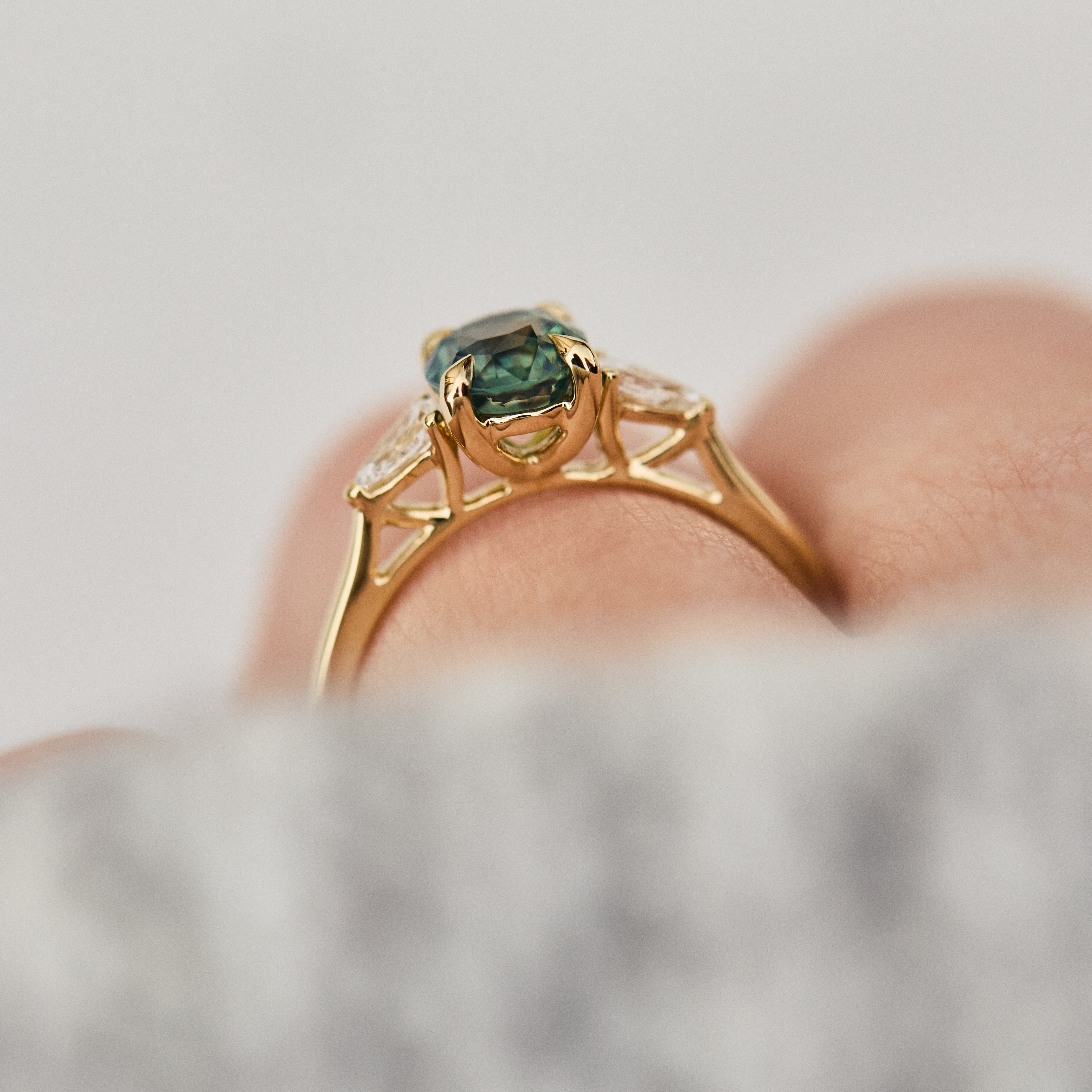 oval green teal sapphire trilogy engagement ring in yellow gold