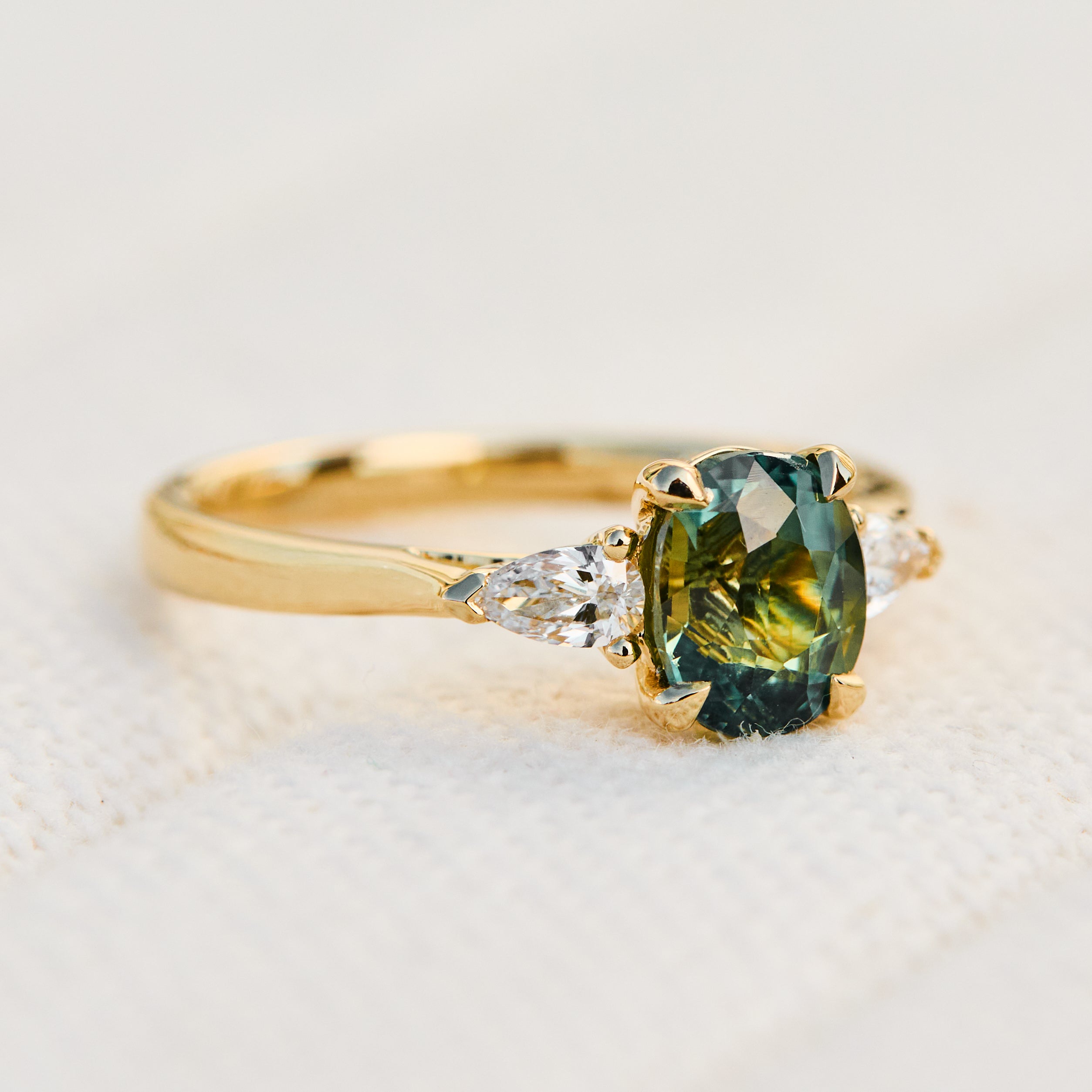 oval green teal sapphire trilogy engagement ring set in 18ct yellow gold
