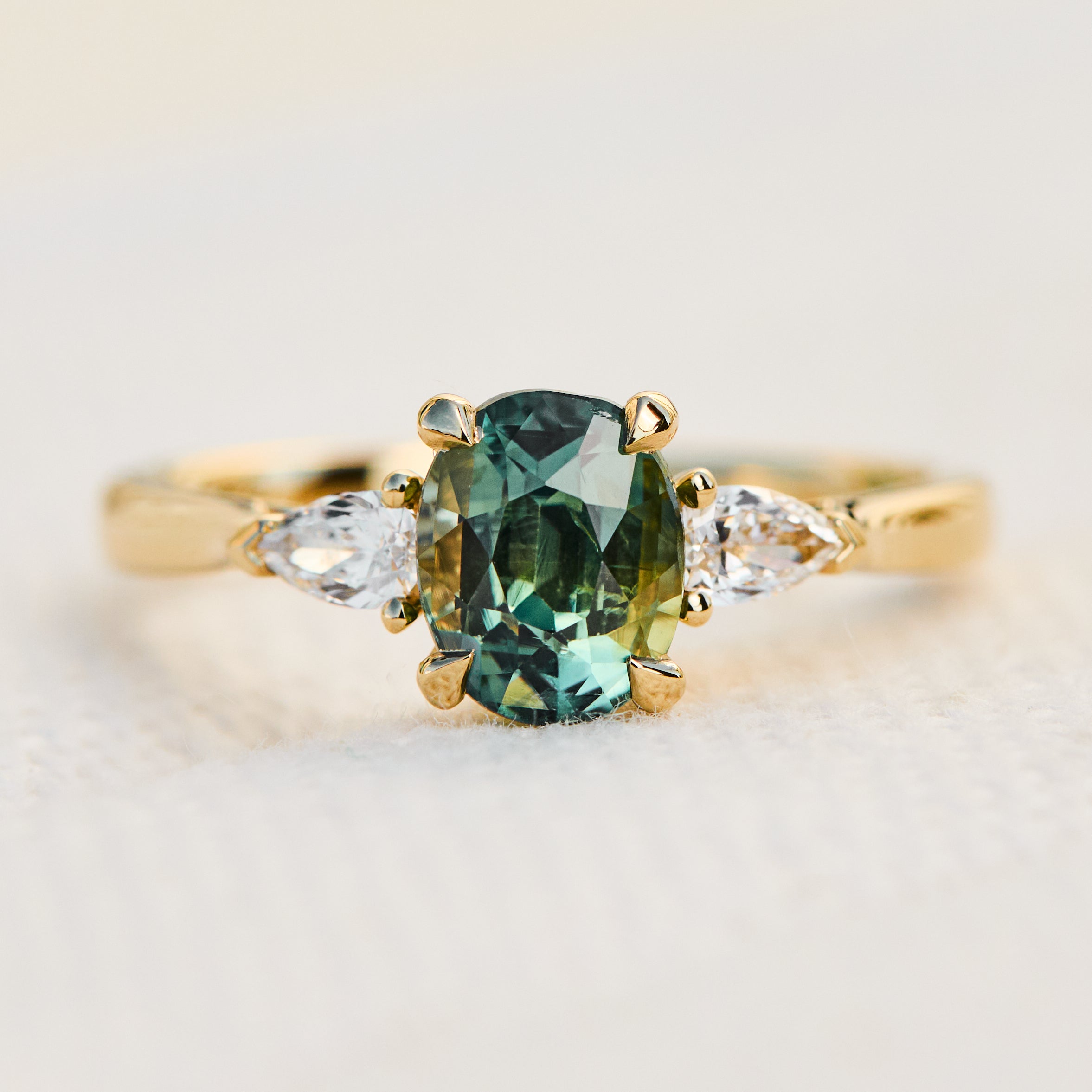 oval green teal sapphire trilogy engagement ring set in 18ct yellow gold