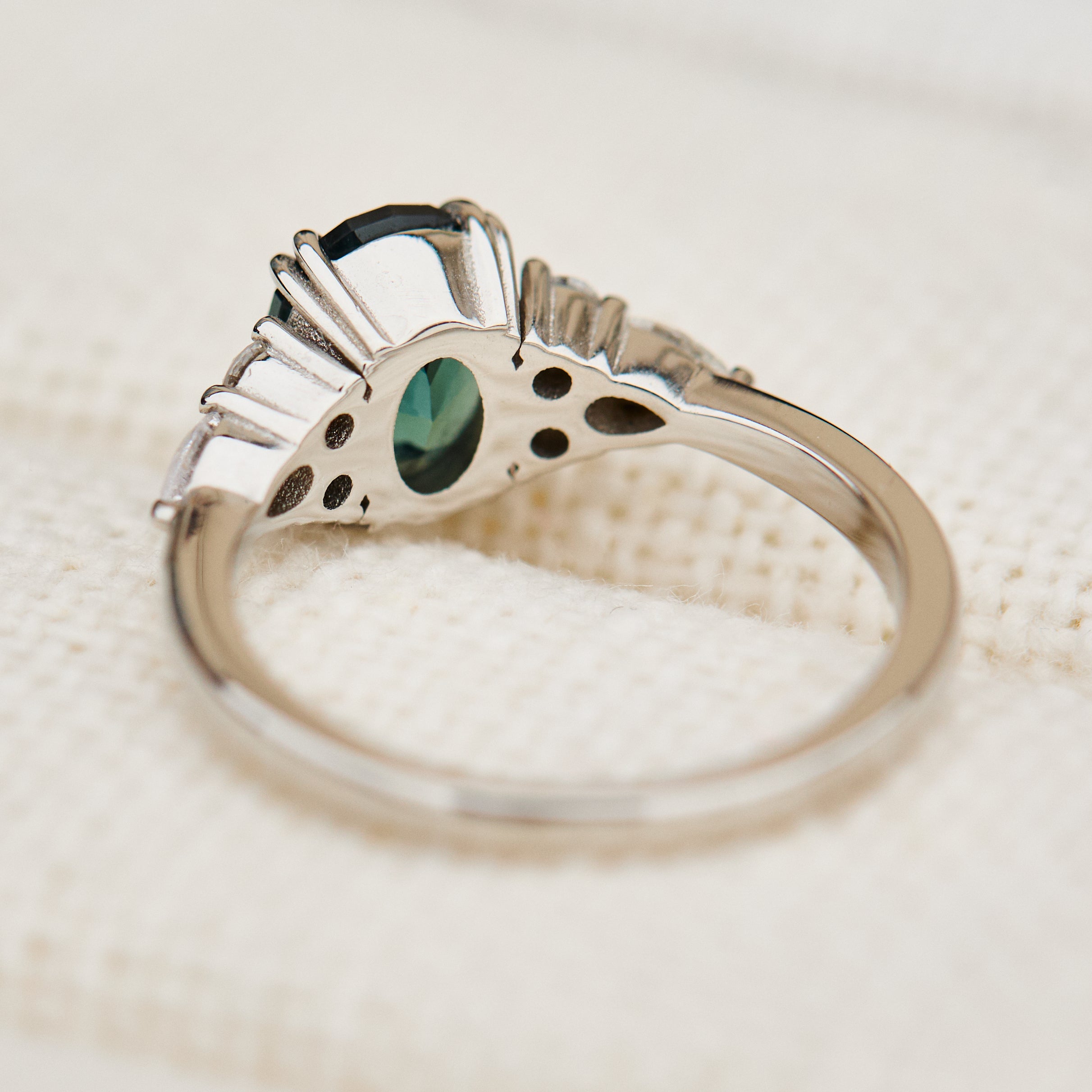oval teal sapphire engagement ring set in platinum accented by six side diamonds