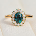 oval teal montana sapphire engagement ring in yellow gold with a diamond halo