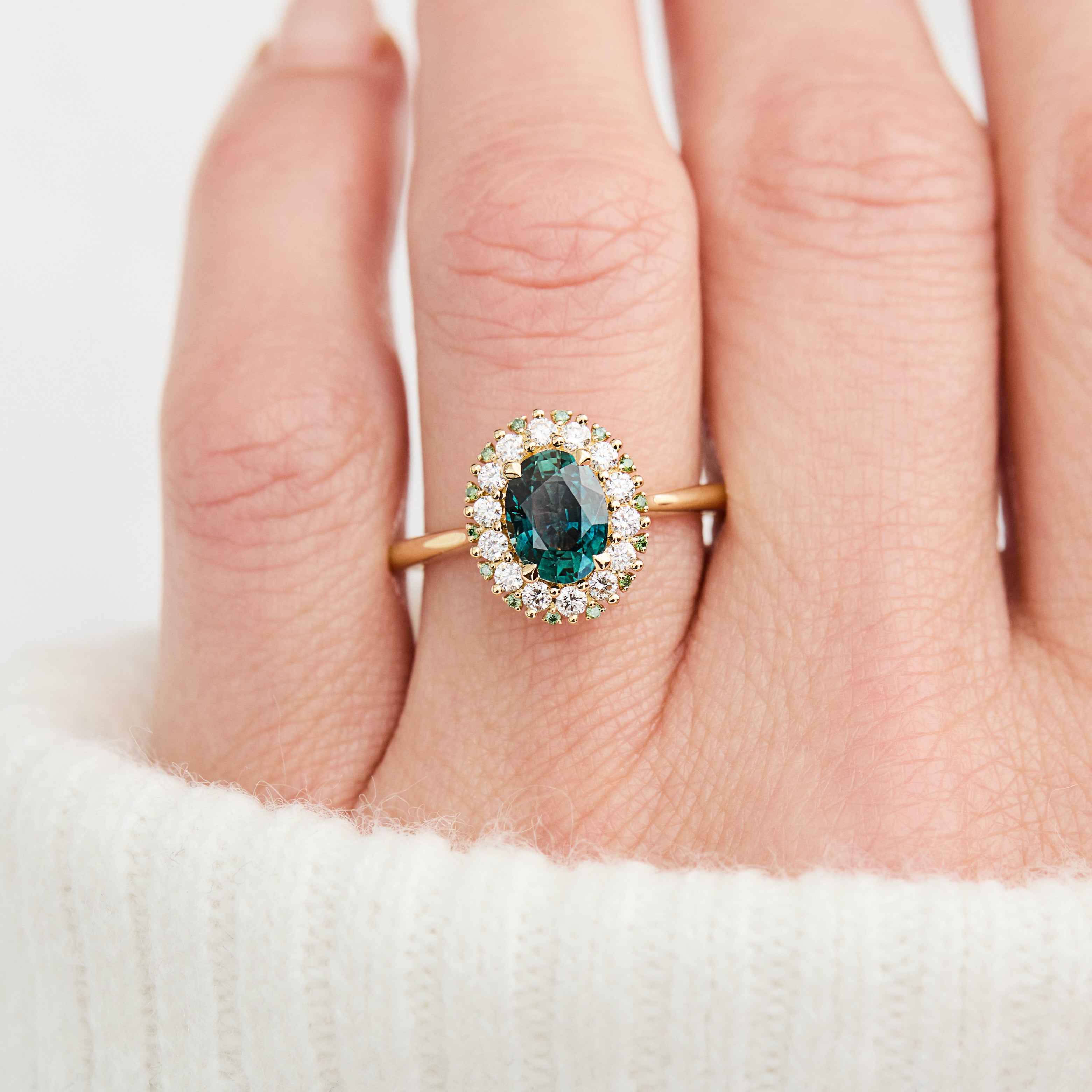 oval teal montana sapphire engagement ring in yellow gold with a diamond halo